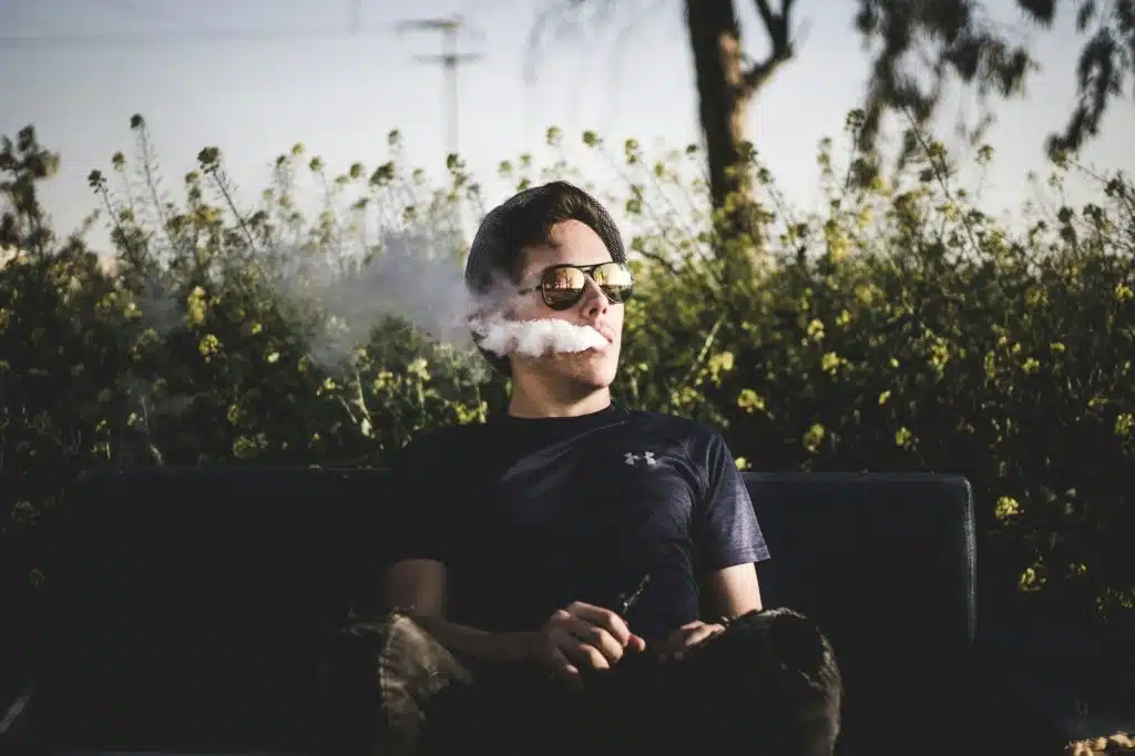 A man sitting on the bench while vaping