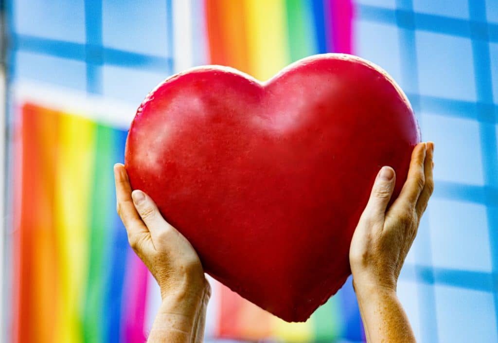 A hand holding a heart shaped balloon