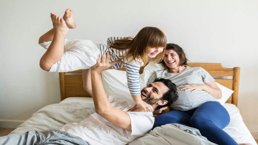 A couple plays with their child inside the bedroom.