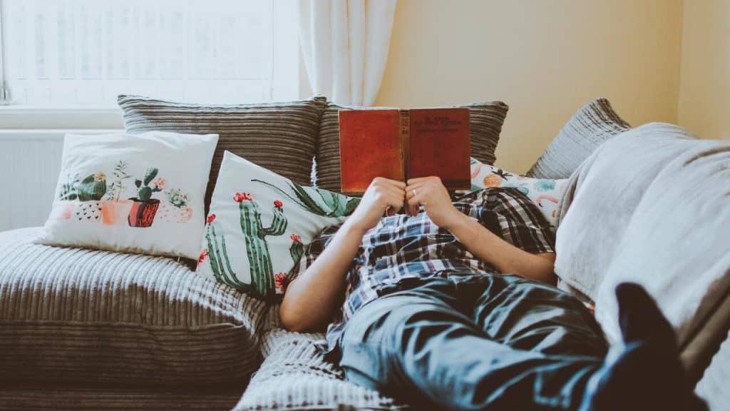 Person laying on the sofa while reading.