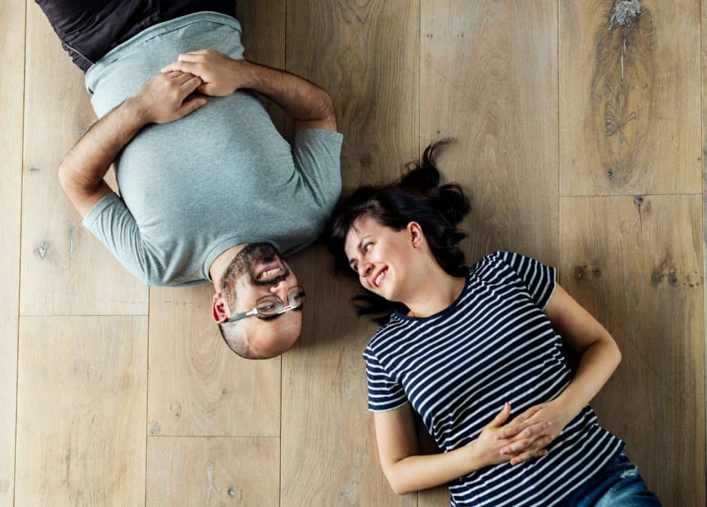 A couple lying on a wooden floor