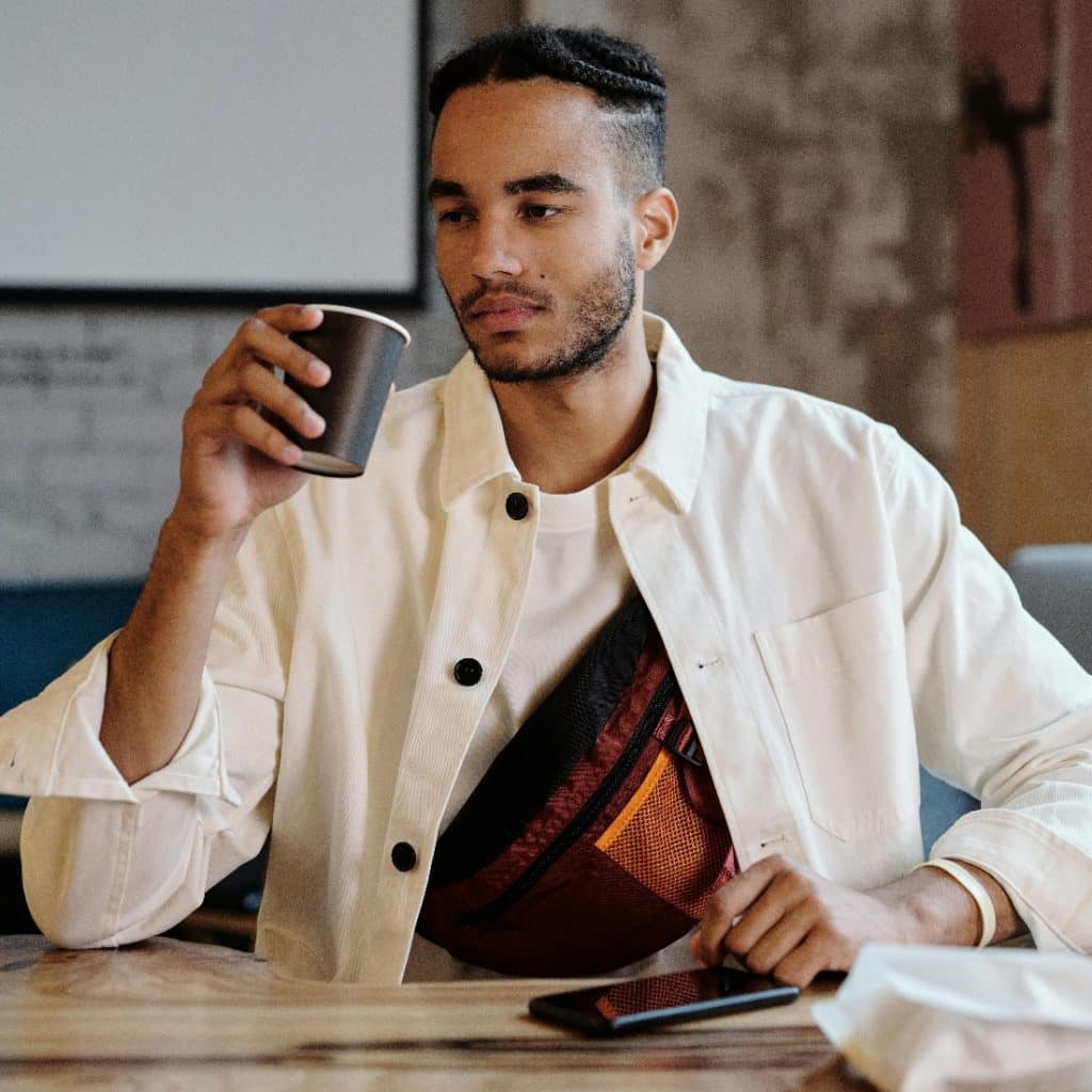 Man in a coffee shop alone and looking emotionally drained while thinking about modern dating