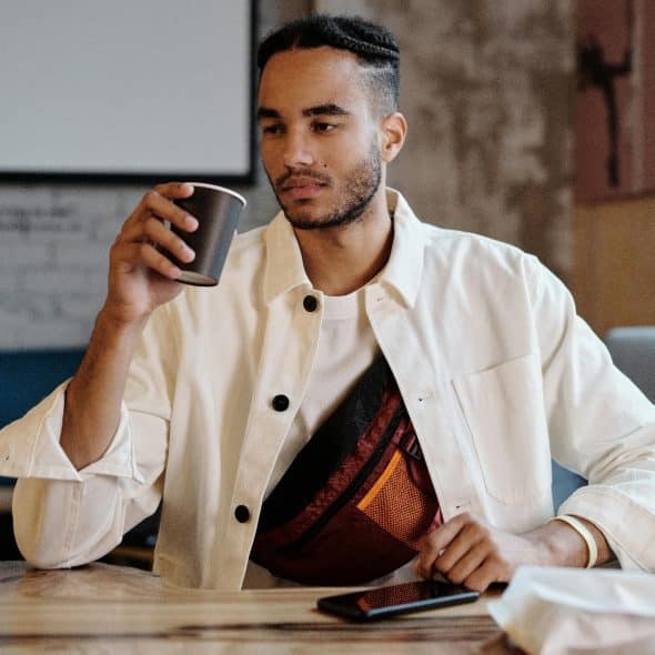 Man in a coffee shop alone and looking emotionally drained while thinking about modern dating