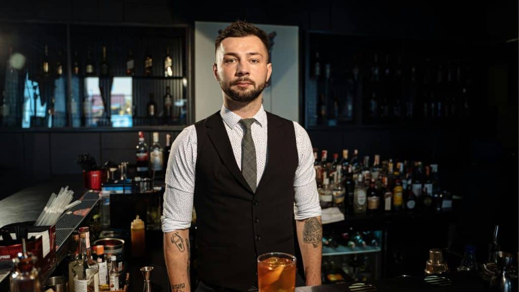 Home bar setup featuring spirits and bar tools neatly arranged with moody lighting.