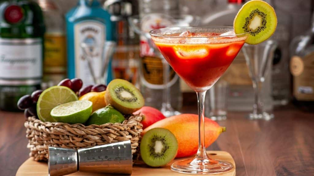 Beginner cocktail tools laid out on a kitchen countertop including a shaker, jigger, strainer and citrus fruits.