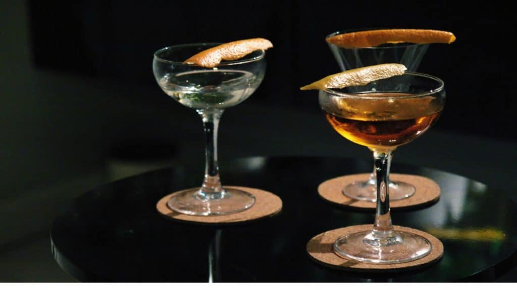 Three classic cocktails presented side by side on a bar surface.