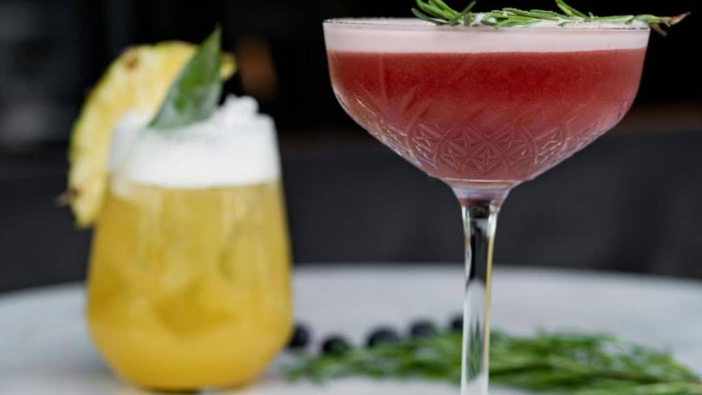Alcohol free cocktail garnished with herbs and citrus, served in elegant glassware on a minimalist white tabletop.