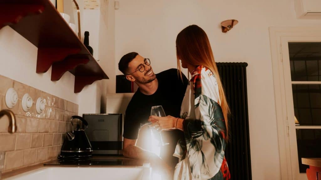 Couple having drinks together in a cozy kitchen, smiling and sharing the experience of crafting cocktails.