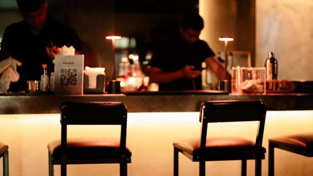 Men standing in a dimly lit bar, thinking of a drink with and enjoying a quiet moment.
