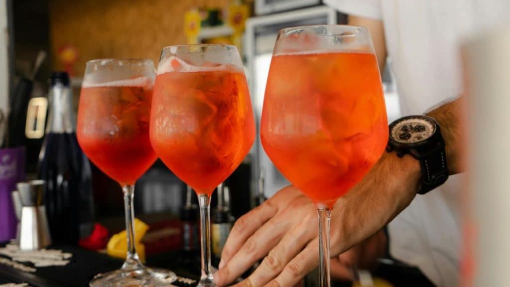 Confident man standing next to his home bar, holding a crafted cocktail.