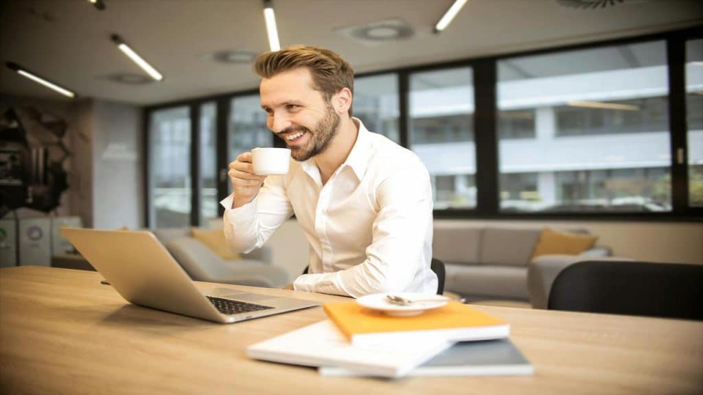 A man smiling in front of a laptop.