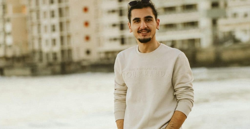 A man walking confidently, hands in pockets, relaxed and smiling.