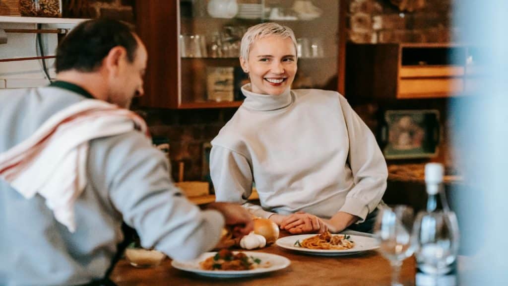 A couple enjoys preparing and sharing a meal in a cozy kitchen.