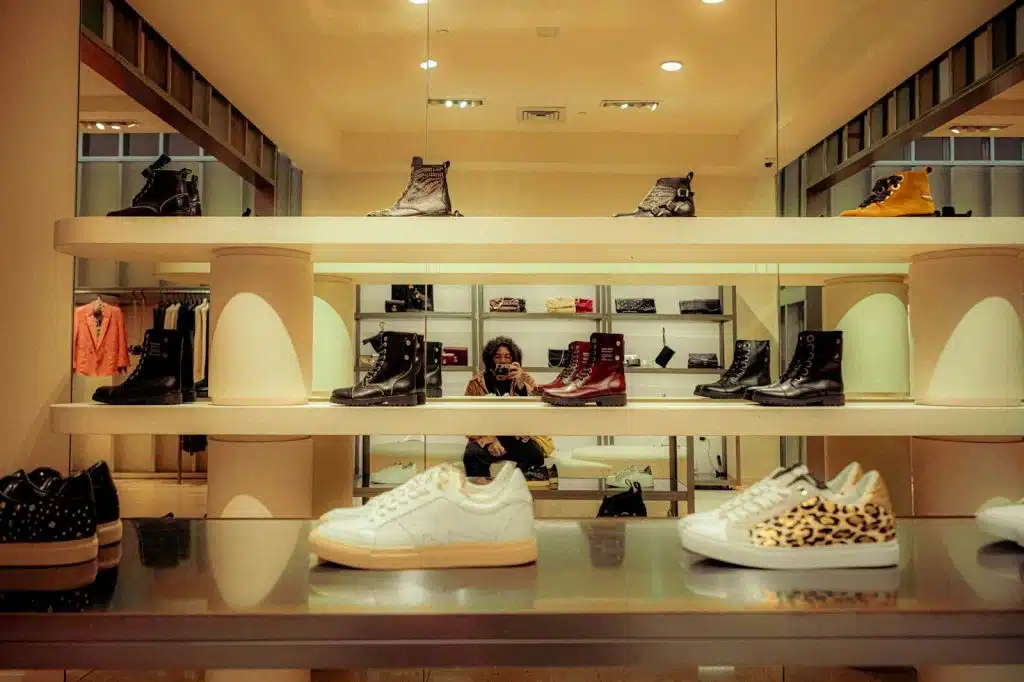 A man taking a mirror shot with different kind of shoes.