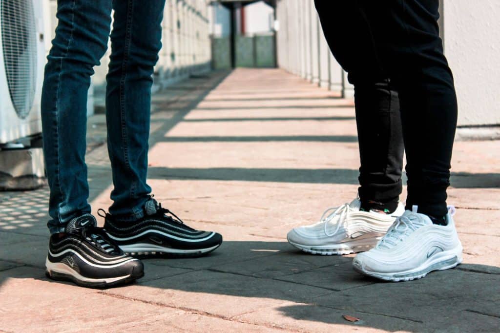 Two men wearing two different shoes and has a different style.