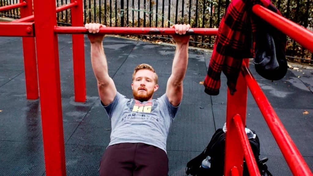 Man performing core-strengthening on workout bars outdoors.