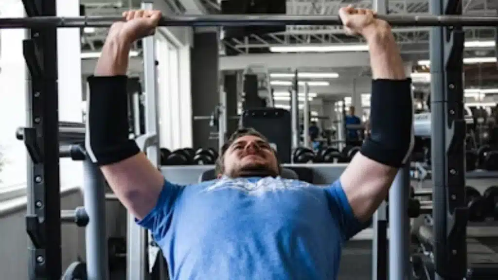 Man lifting weights in gym to build muscle and burn fat.