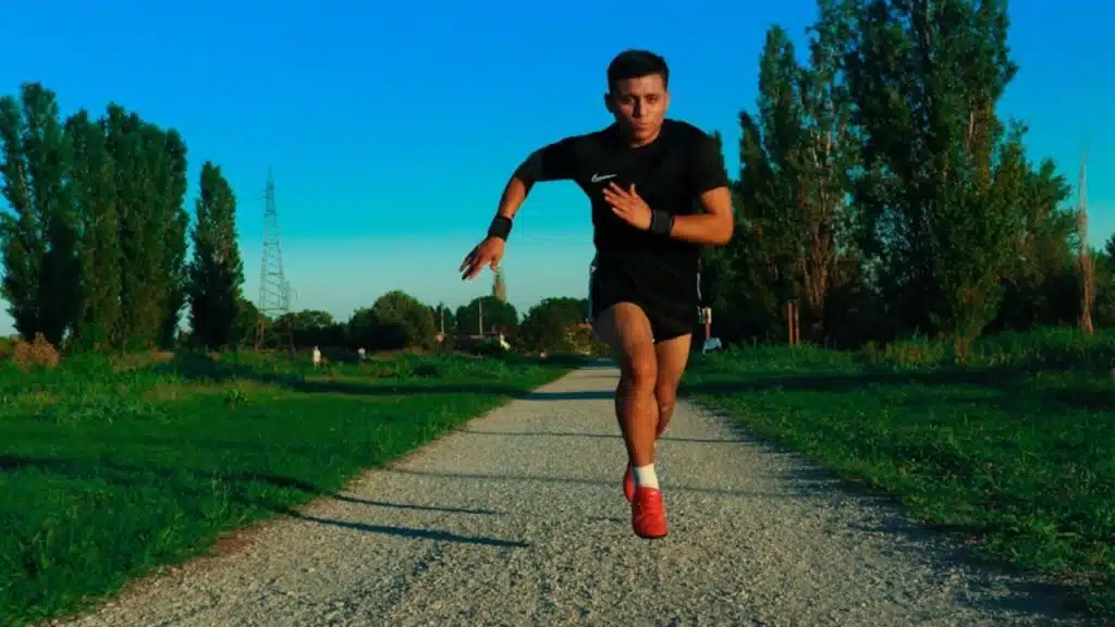 Male runner doing high intensity interval sprint in city park.