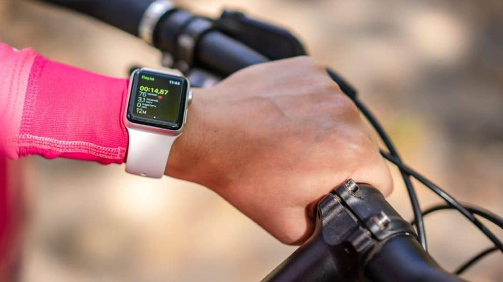 Man using fitness tracker while riding a bike to monitor activity levels.