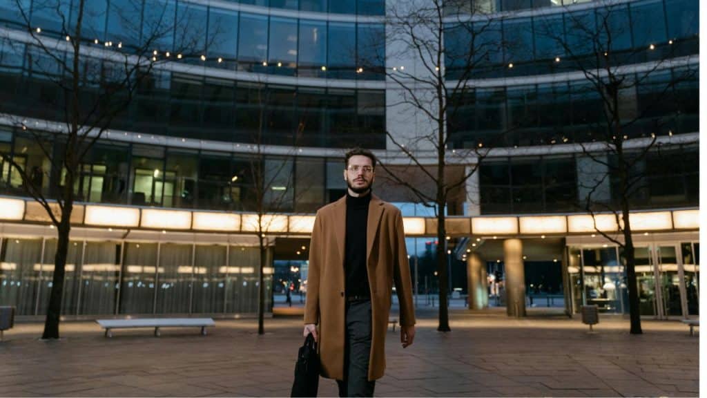 Man in modern attire walking calmly through a city, staying grounded amidst chaos.