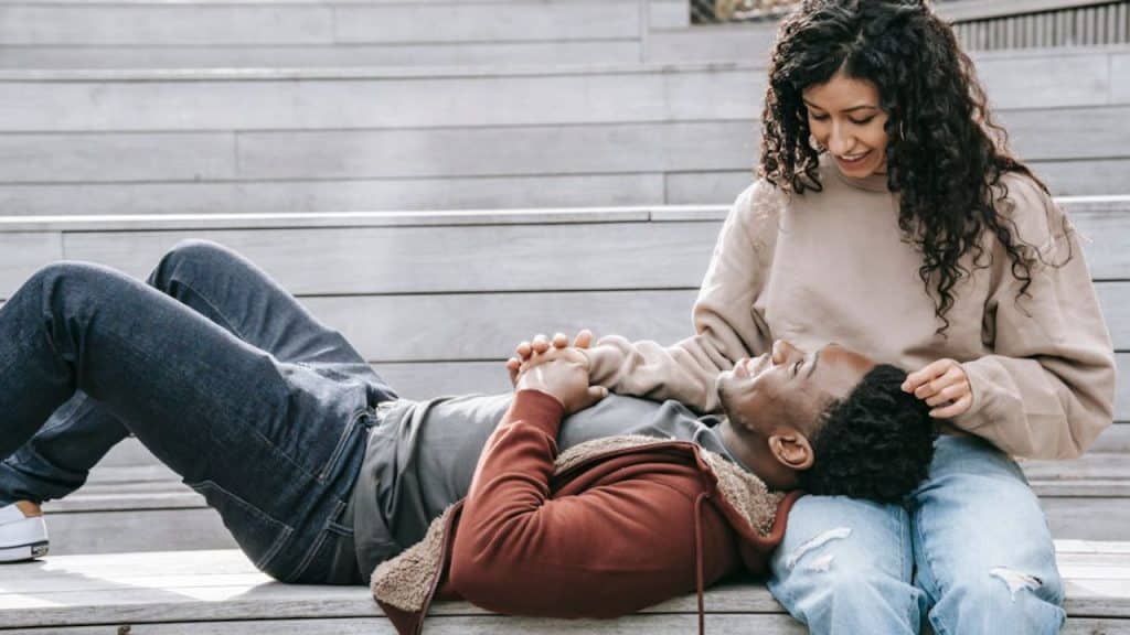 A man attentively listening to his partner while they talk on a park bench.