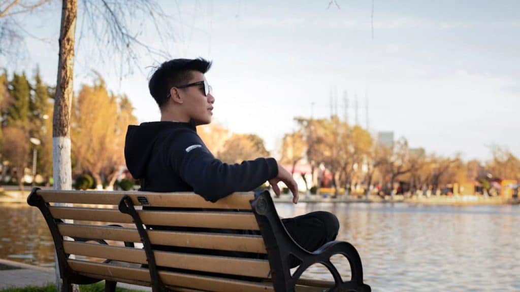 Man sitting by the lake in silent reflection, cultivating calmness and emotional balance.