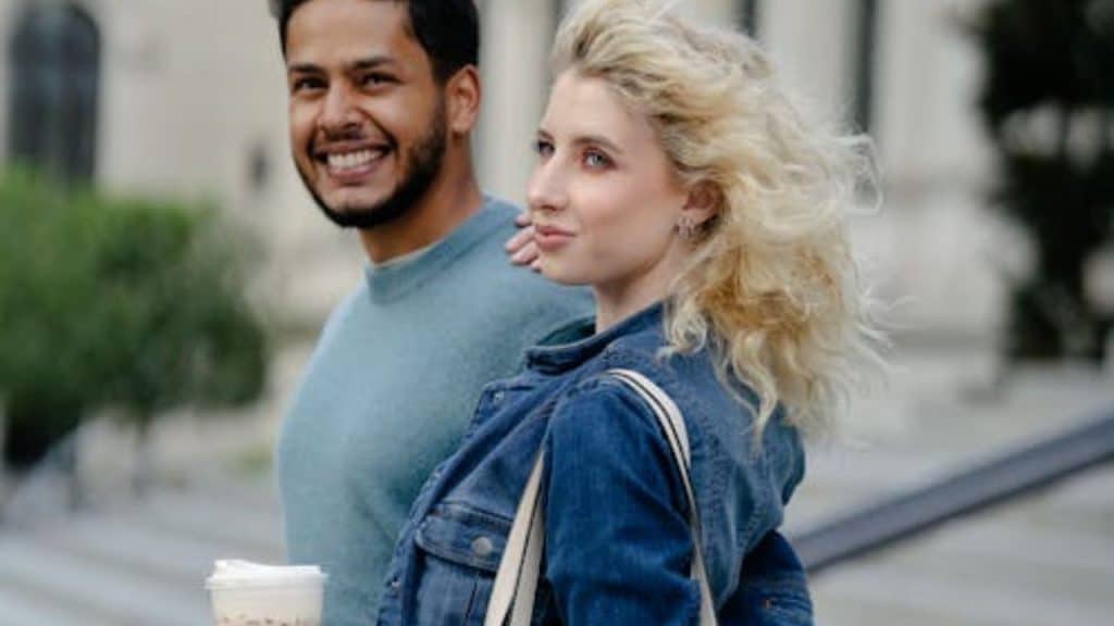 Man and woman walking side by side in public, smiling.