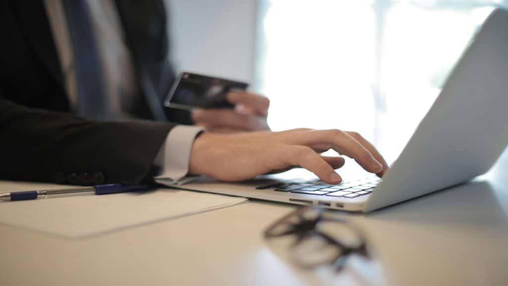 A man in a suit uses a laptop making an online purchase.