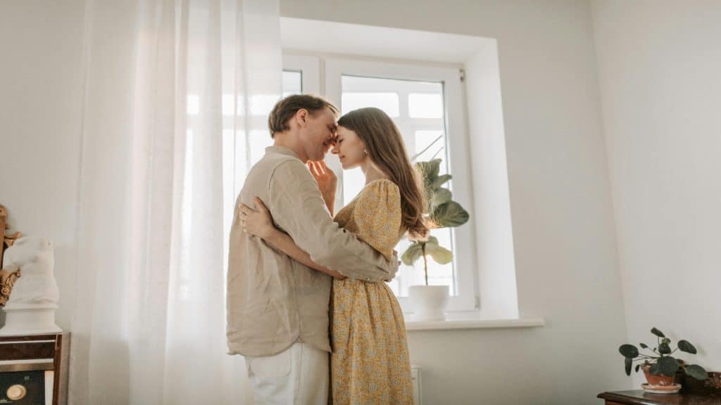 A couple embracing each other closely with their foreheads touching.