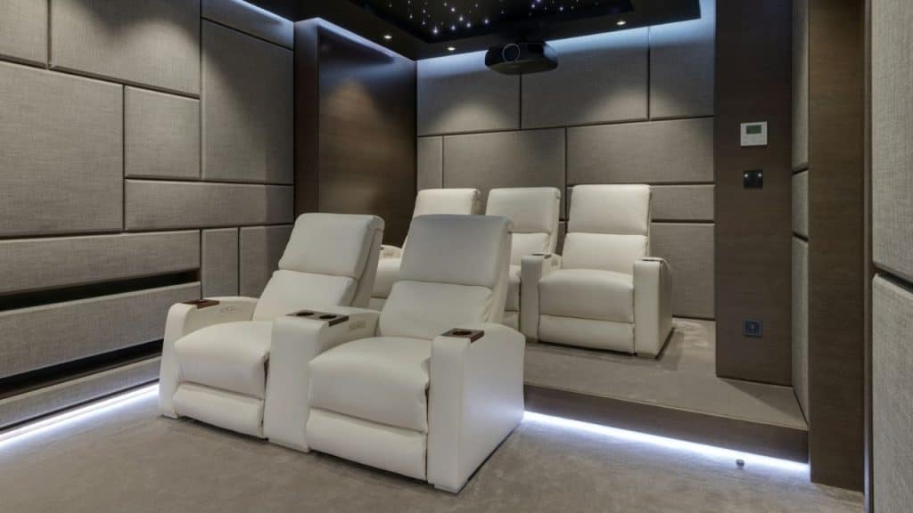 A luxurious home theater features rows of white recliners and a ceiling with star-like lights.