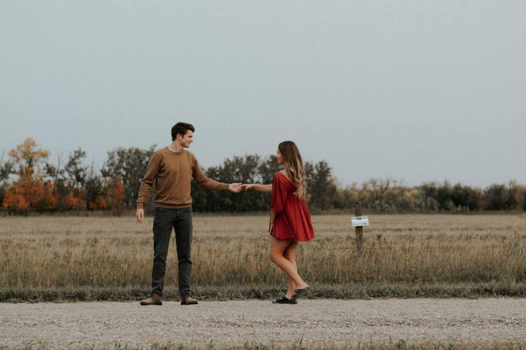 A man and woman holding hands beside the road
