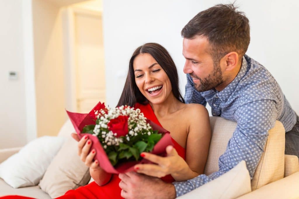 A woman smiling because of a flower from a man 