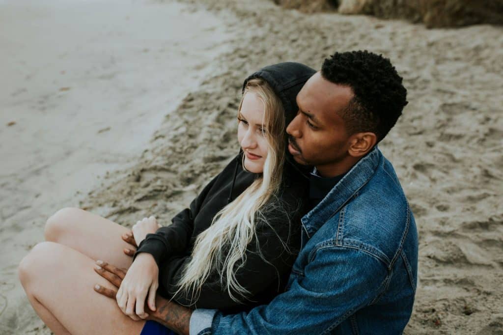 A man without expression hugging a woman