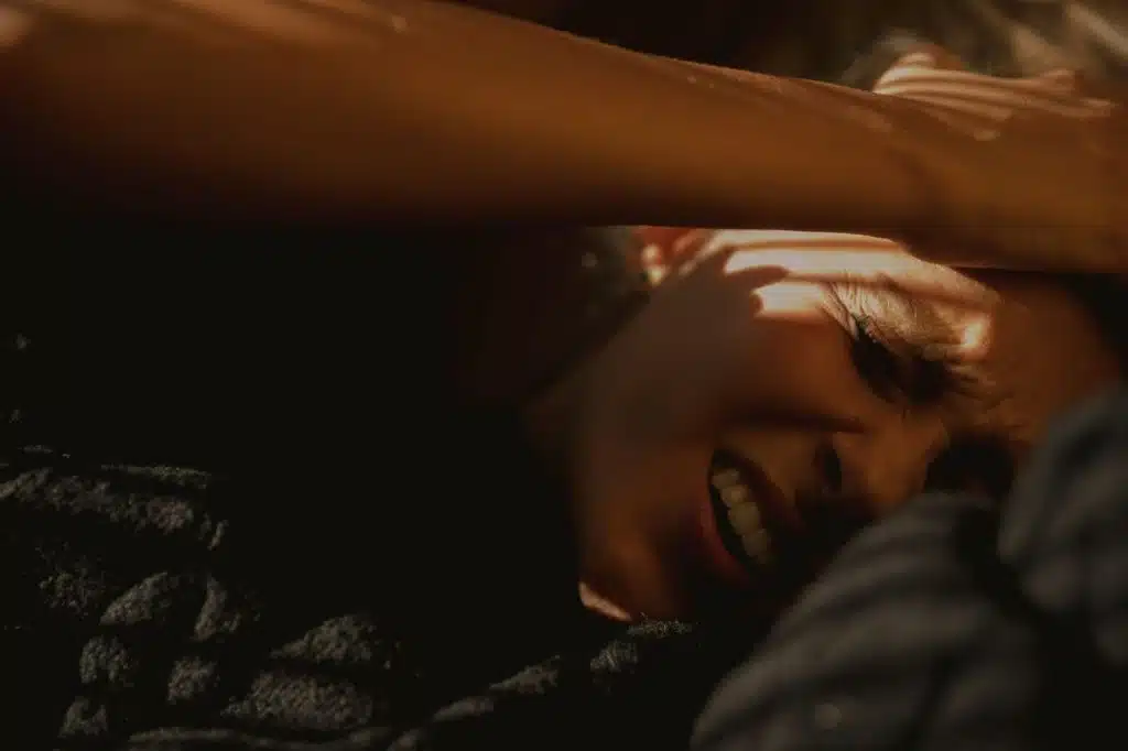 A close-up picture of a person in pain while lying on bed.
