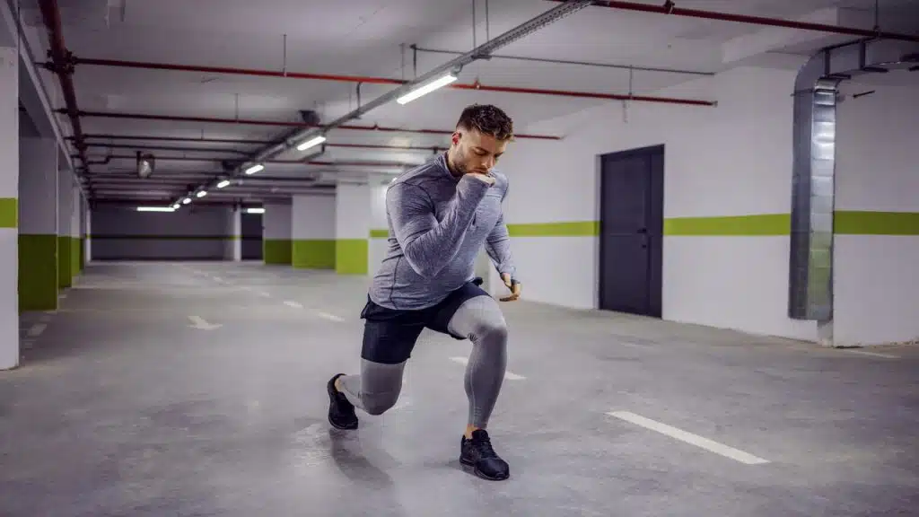 A man doing a lunge at a parking lot.