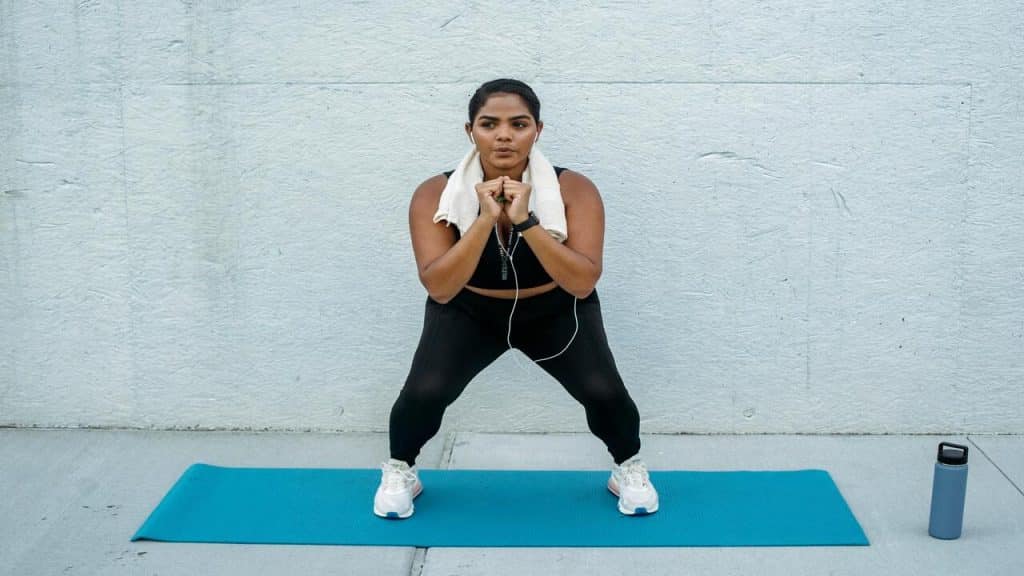 A woman squatting on a yoga mat.
