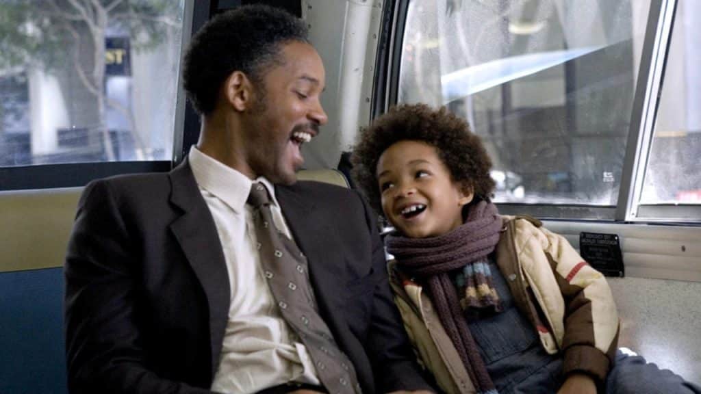 A father and son smiling at each other inside a bus.