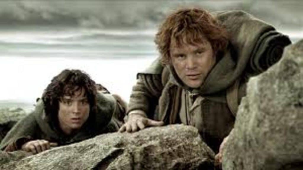 Two hobbits hiding behind some mountain rocks.