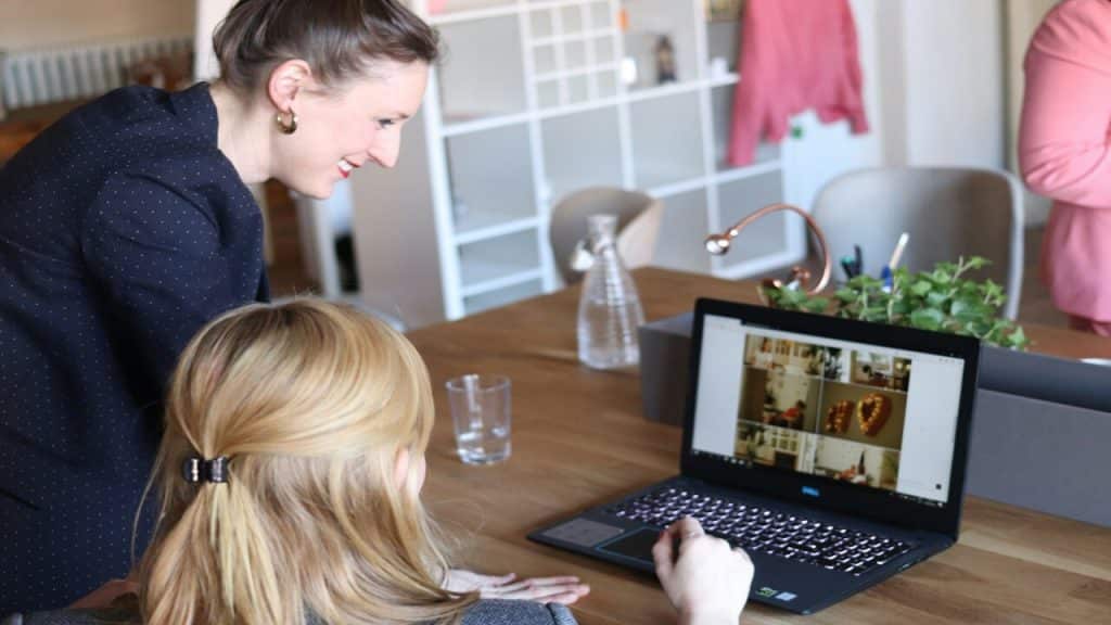 Two women smiling at their laptop at work