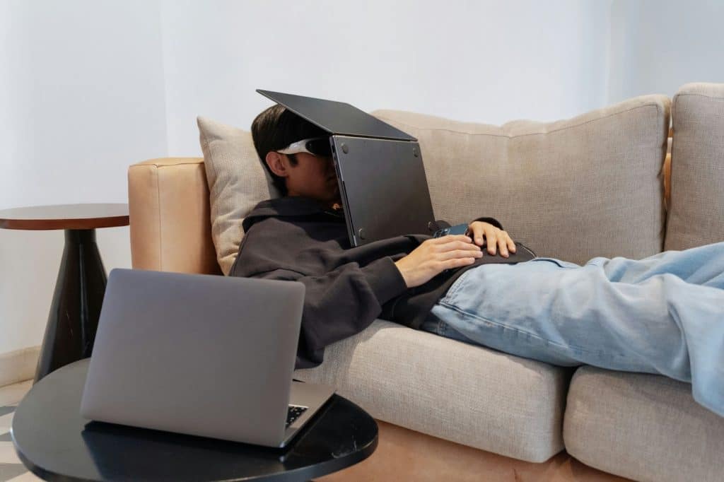 A man resting with a laptop on his face