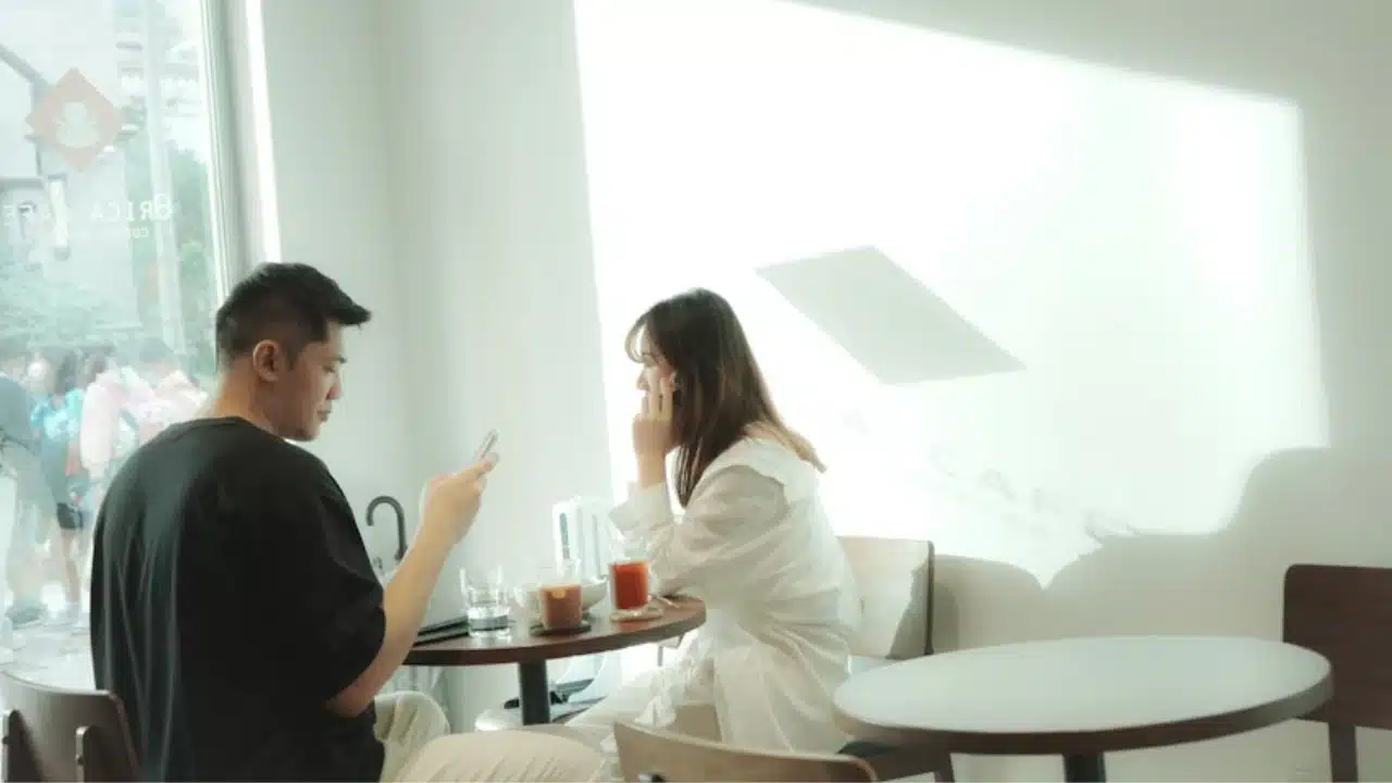 Couple busy with their phones while eating together without full attention on each other.