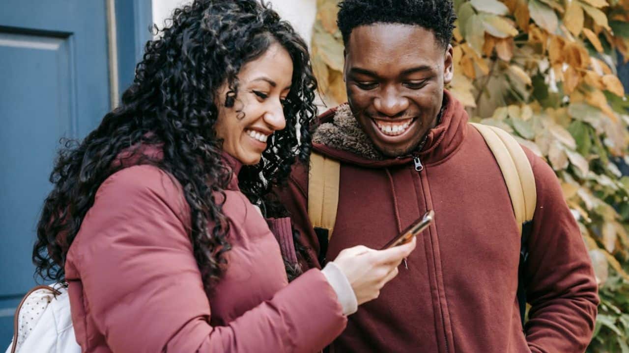 Couple looking at their phone together, deciding what to post.