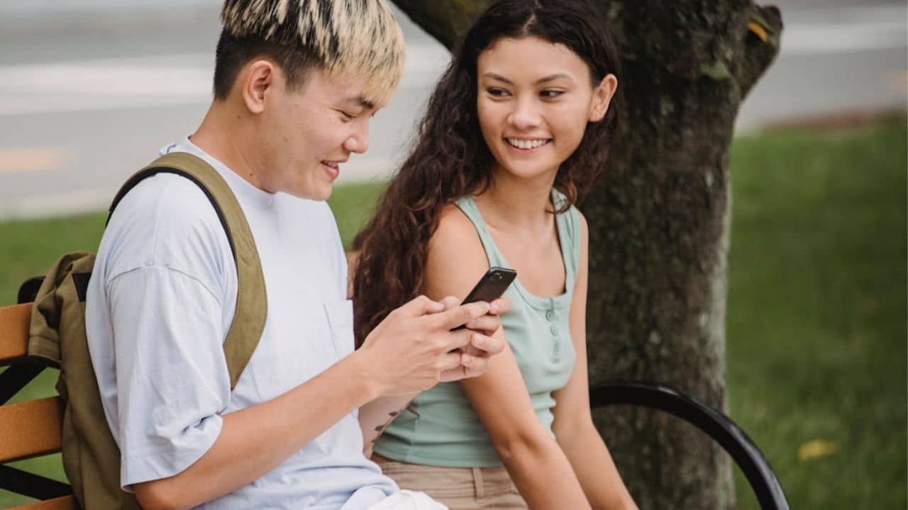 Man reading a DM and replying firmly with his partner nearby