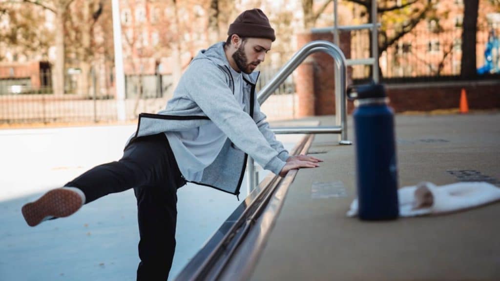 Man warming up near an urban platform, dressed for outdoor fitness