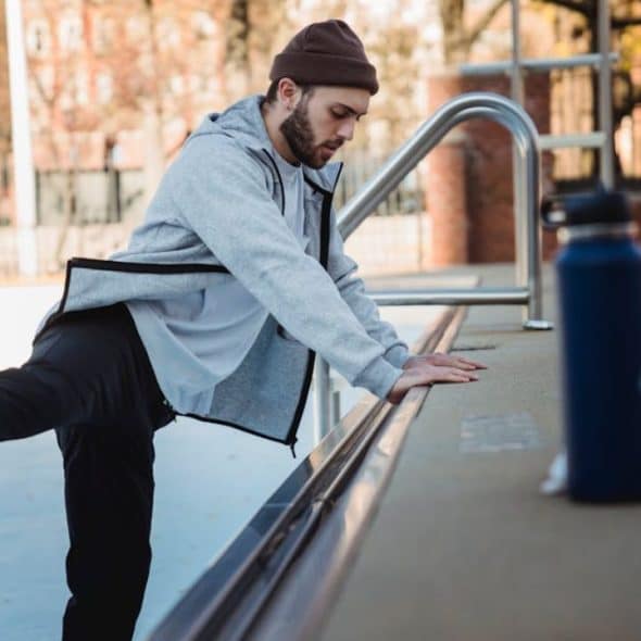 Man warming up near an urban platform, dressed for outdoor fitness