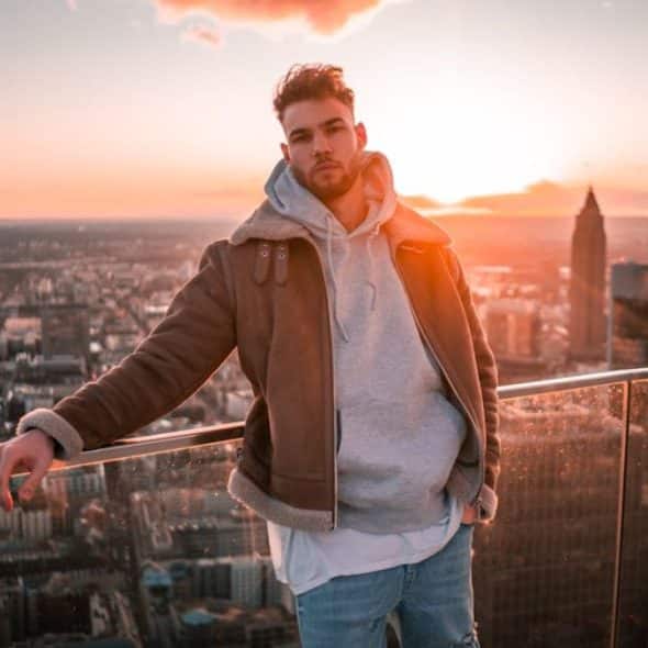 Man standing alone on a rooftop at sunset, deep in thought about his relationship