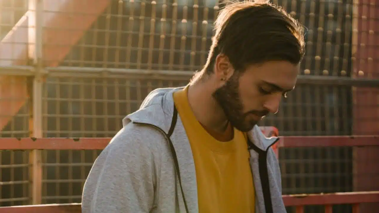 Man alone on a city rooftop at sunset, deep in thought.