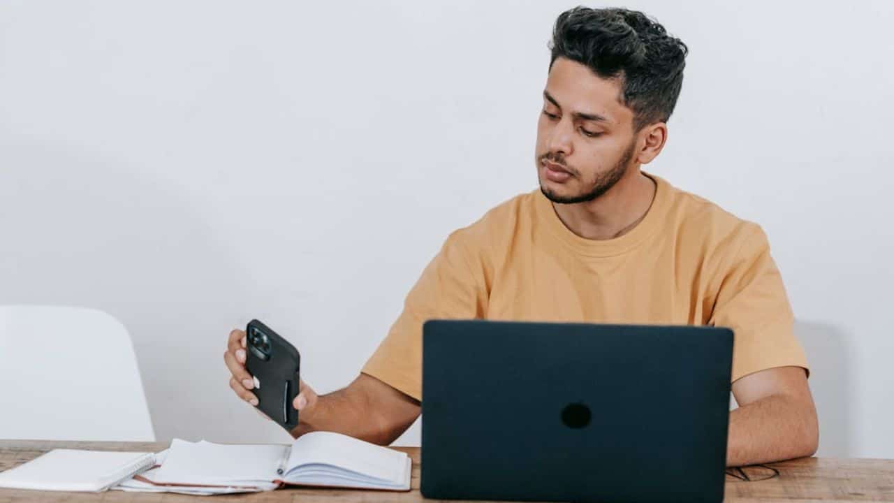 Man holding his phone, resisting the urge to message.