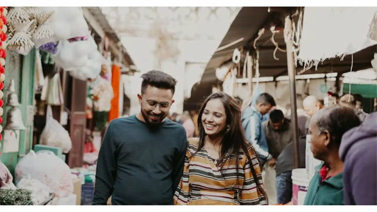 A couple walking confidently through a public space, smiling despite onlookers.