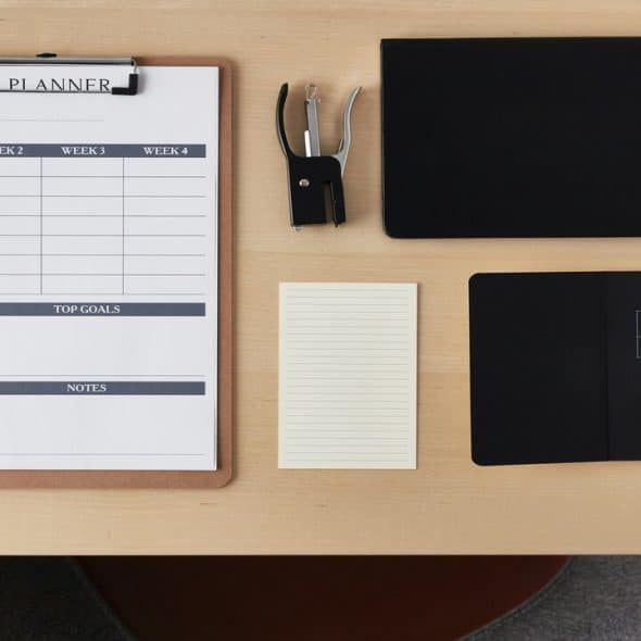 A desk with a calendar, notebook, and more.